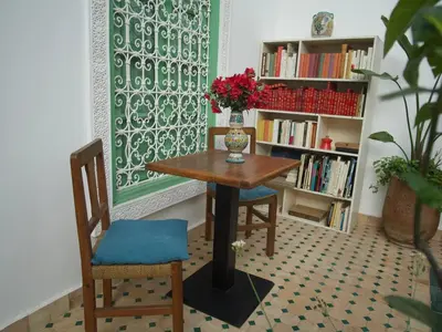 a room with a table and two chairs and a book shelf at Riad Ocallaghan in Marrakech