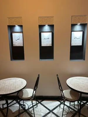 two tables and chairs in a room with three pictures on the wall at Riad Amazing Amazigh avec jacuzzi petit déjeuner compris avec aussi chambres familiales près de la place jemaa El fna in Marrakech