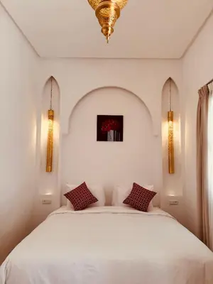 a bedroom with a white bed with two pillows at Riad El Khaeir - Piscine, Hamam & Spa in Marrakech