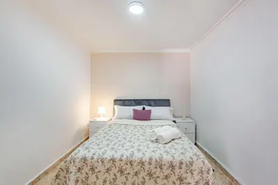 a white bedroom with a bed with a purple pillow at Cosy apartment in the heart of Hivernage in Marrakech