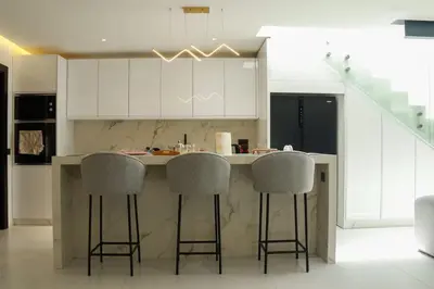 a kitchen with white cabinets and bar stools at Duplex piscine chauffée terrasse in Marrakech