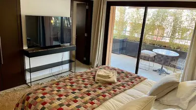 a bedroom with a bed and a view of a patio at Appartement de luxe a Care Eden in Marrakech