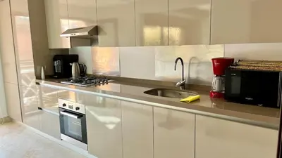 a white kitchen with a sink and a microwave at Appartement de luxe a Care Eden in Marrakech