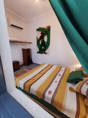 two beds in a white room with green curtains at Riad EL BADI in Marrakech
