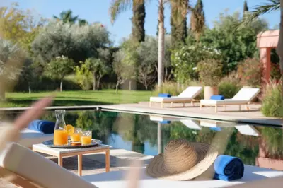 a pool with a table with glasses of orange juice at Villa JENAMAN in Marrakech