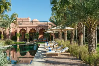 a row of chairs and umbrellas next to a pool at Villa JENAMAN in Marrakech