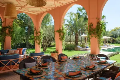 a dining room with a table and chairs and a pool at Villa JENAMAN in Marrakech