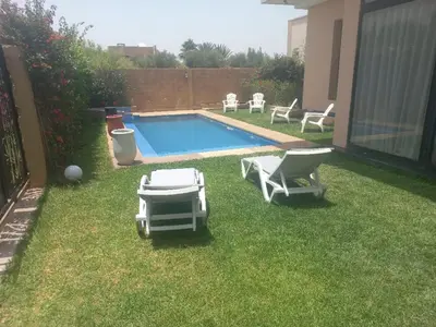 a backyard with a swimming pool and two lawn chairs at H Amelkis in Marrakech