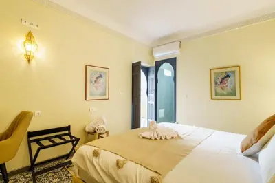 a bedroom with a large bed and a chair at Riad Taher Bed & Breakfast - Top position Médina in Marrakech