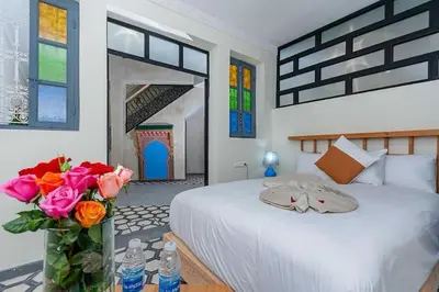 a bedroom with a large bed with a vase of flowers at Riad Taher Bed & Breakfast - Top position Médina in Marrakech