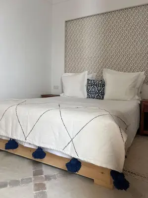 a bedroom with a large white bed with blue trim at Riad Anahata Marrakech in Marrakech