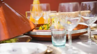 a table with wine glasses and a plate of food at Riad Anahata Marrakech in Marrakech