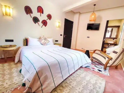 a bedroom with a bed and a table and a chair at Domaine Homa Marrakech in Marrakech