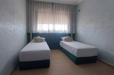 two beds in a small room with a window at Luxury city center apartment with swimming pool in Marrakech