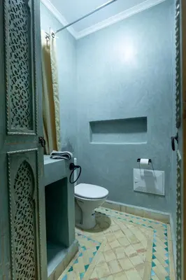 a blue bathroom with a toilet and a sink at Riad LALLA JIHANE in Marrakech