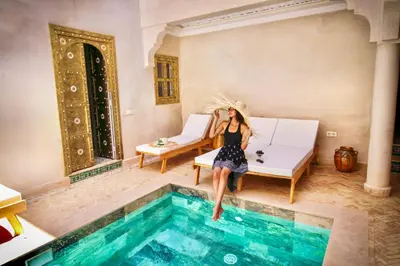 a woman jumping into a swimming pool at Riad LALLA JIHANE in Marrakech