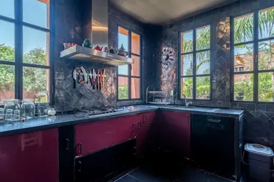 a large kitchen with red cabinets and windows at Designer Villa in La Palmeraie Marrakech in Marrakech