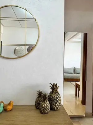 a mirror hanging on a wall with two pineapples on a table at À 6 min du stade - Résidence avec Piscine, Wifi, Gardien H24 in Marrakech