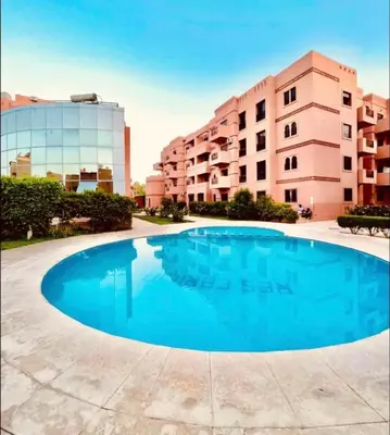 a large blue swimming pool in front of a building at À 6 min du stade - Résidence avec Piscine, Wifi, Gardien H24 in Marrakech