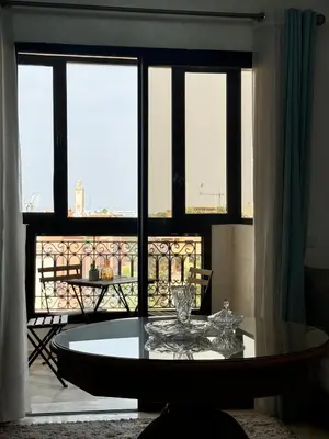 a glass table in a room with a large window at À 6 min du stade - Résidence avec Piscine, Wifi, Gardien H24 in Marrakech