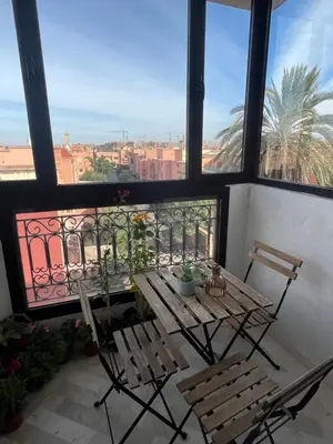 a balcony with a wooden table and two chairs at À 6 min du stade - Résidence avec Piscine, Wifi, Gardien H24 in Marrakech