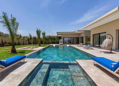 a swimming pool with two blue chairs and a house at Villa luxueuse sans vis à vis - Piscine chauffée in Marrakech