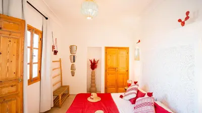 a bedroom with a bed with red and white pillows at Riad Marssa, Privé Zen avec belle piscine dans la Médina in Marrakech