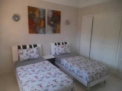 a bedroom with two beds and a cabinet at App spacieux marrakech centre ville in Marrakech