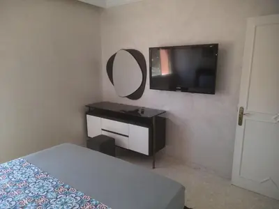a bedroom with a bed and a mirror and a television at App spacieux marrakech centre ville in Marrakech