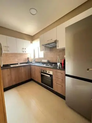 a kitchen with wooden cabinets and a stainless steel refrigerator at Appartement moderne au Golf in Marrakech