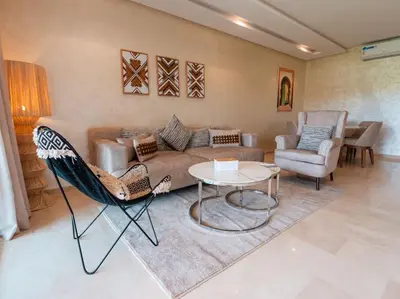 a living room with a couch and a table and chairs at Magnifique appartement 3 chambres à Prestigia in Marrakech
