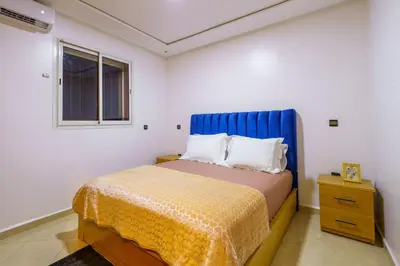 a bedroom with a bed with a blue headboard and a window at Appartement Cosy et calme in Marrakech