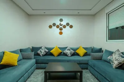 a living room with a blue couch with yellow pillows at Appartement Cosy et calme in Marrakech