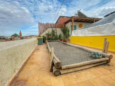 a patio with a yellow building and a fence at Riad privé, 5 suites et piscine in Marrakech