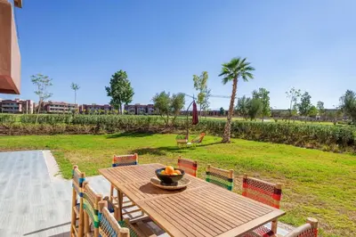 a wooden table and chairs with a bowl of fruit on it at Luxurious Apartment Marrakech with Pool, Golf, Private Garden in Marrakech