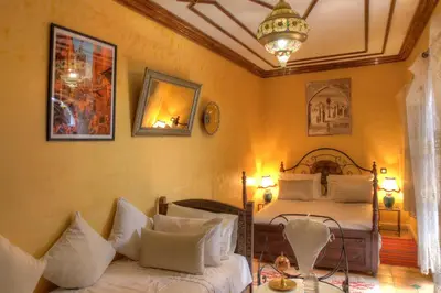 a bedroom with two beds and a chandelier at Riad ELIZZI in Marrakech