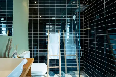 a black tiled bathroom with a shower and a toilet at le petit dar alwalidine in Marrakech