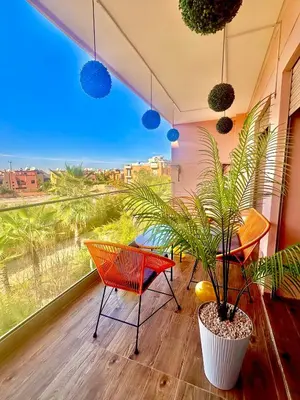 a room with a table and chairs and a plant at Elegant Apartment with Pool, Clim & Wi-Fi - 7min Gueliz in Marrakech
