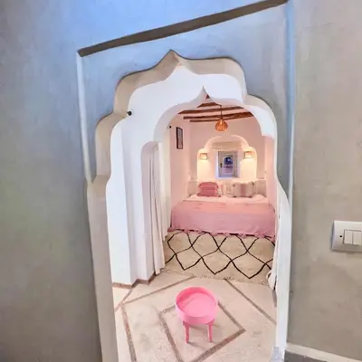 a room with a bed and a pink stool at Riad Ouatine in Marrakech