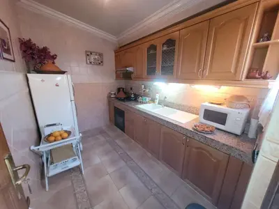 a kitchen with wooden cabinets and a white refrigerator at MELBARI Cosy-Appart in Marrakech