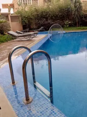 a swimming pool with a ramp leading into the water at Le Fairouz Appartement Haut Standing centre ville Piscine in Marrakech