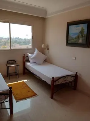 a bedroom with a bed in a room with a window at Le Fairouz Appartement Haut Standing centre ville Piscine in Marrakech
