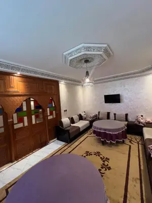 a living room with a couch and a table at Charmant appartement spacieux avec cour fleurie et Hammam à Targa Marrakech in Marrakech