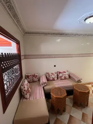 a living room with a couch and a table at Charmant appartement spacieux avec cour fleurie et Hammam à Targa Marrakech in Marrakech