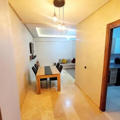 a dining room with a table and chairs in a room at Appartement haut standing plein centre gare in Marrakech