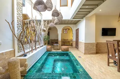 a pool in the middle of a room with a table and chairs at Riad Zatiah Exclusive and chic breakfast incl in Marrakech