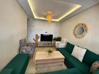 a living room with a green couch and a tv at Appartement de luxe en face la gare à gueliz marrakech in Marrakech