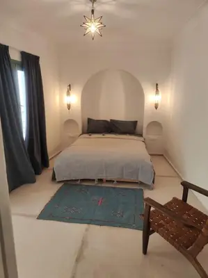 a bedroom with a bed and a bench in it at Riad White Cactus in Marrakech