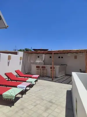 a row of red and green chairs on a roof at Riad White Cactus in Marrakech