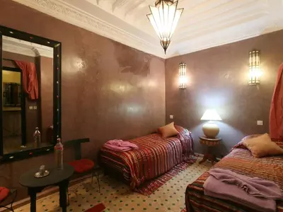 a room with two beds and a mirror and a lamp at Riad El Bellar in Marrakech